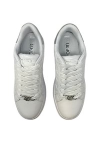 Sneaker bianchi con una superficie in pelle liscia, lacci testurizzati e un accento di logo metallico sulla parte anteriore. Design a bassa altezza con punte arrotondate.