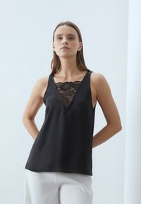 Top negro sin mangas con un profundo escote en V y inserción de encaje. Fabricado en una tela suave, presenta un corte relajado y un diseño minimalista sin adornos.