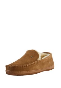 Bruine suède slipper met een schapenvachtvoering, gesloten achterkant, gestikte details en een rubberen zool, voorzien van een klein logo-embleem aan de zijkant.