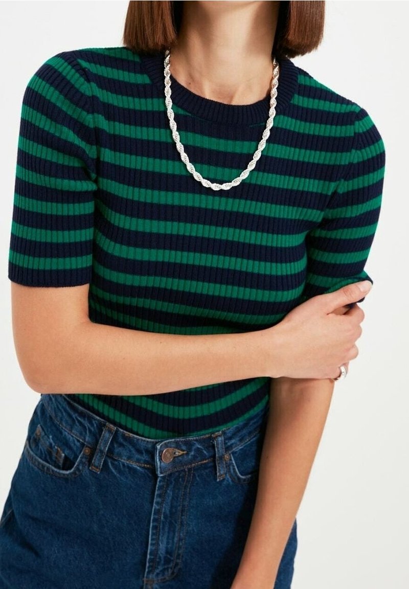 Haut en maille côtelée à rayures dans des tons bleu marine et vert, col rond, manches courtes, associé à une jupe en denim, présentant un motif texturé.