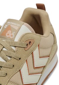 Baskets beiges avec un dessus en daim texturé et en mesh, accentuées de cuir blanc, arborant un design en zigzag et des détails orange contrastés.