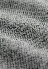 Pleteni materijal u sivim tonovima, s teksturiranim, rebrastim uzorkom. Mekan i fleksibilan materijal s suptilnim varijacijama u nijansi.