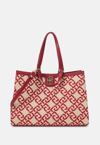 Sac fourre-tout beige présentant un motif rouge entrelacé, des accents en cuir rouge lisse, deux poignées et une fermeture à clip dorée.