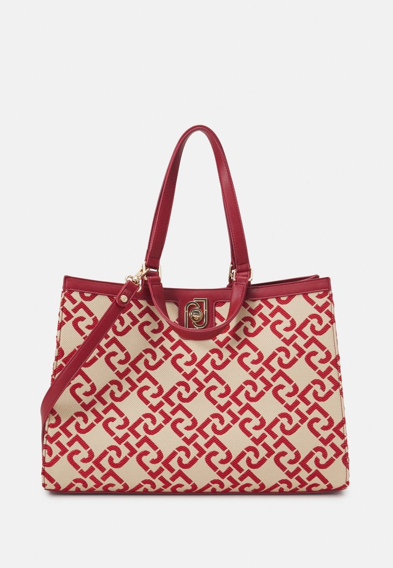 Sac fourre-tout beige présentant un motif rouge entrelacé, des accents en cuir rouge lisse, deux poignées et une fermeture à clip dorée.
