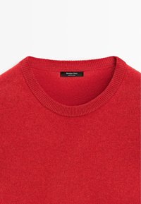 Červený pletený svetr s kulatým výstřihem, žebrovanými detaily na límci a měkkou strukturou. Štítek nese nápis "Massimo Dutti, Vyrobeno v Číně."