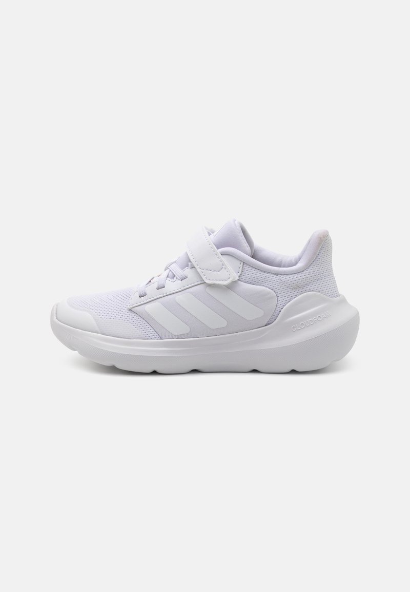 Zapatillas deportivas blancas con parte superior de malla, cuello acolchado y correa de gancho y bucle. Presenta tres rayas blancas en el costado y suela texturizada.