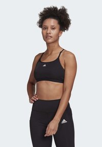 Črn športni crop top iz gladkega materiala s tankimi naramnicami in belim Adidasovim logotipom. V kompletu z ujemajočimi se visokimi legicami.
