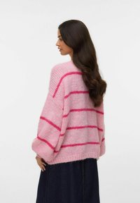 Ροζ πουλόβερ σε υπερμεγέθη μέγεθος με πιο ανοιχτόχρωμες ροζ ρίγες. Κατασκευασμένο από μαλακό, χνουδωτό υλικό, με ριμπ τελείωμα και φουσκωτά μανίκια.