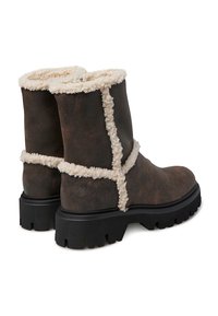 Stivali in shearling marrone foderati, con una robusta suola nera, caratterizzati da un caldo bordo color crema e un design semplice e resistente.