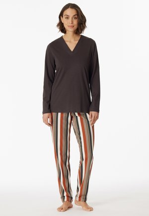 Dunkelgraues langärmeliges V-Neck-Top kombiniert mit mehrfarbigen gestreiften Hosen in horizontalen Streifen in Orange, Grün und Creme.