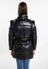 Giacca a puffo nera con finitura lucida, colletto alto e vita belted. Texture trapuntata con dettagli arricciati e maniche lunghe.