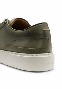 Green leather sneaker with a chunky white sole, featuring subtle stitching, a copper accent on the heel, and a smooth texture.