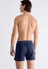 Boxers en coton bleu marine avec une taille élastique et un petit logo. Texture lisse et design ajusté, offrant de la place pour le mouvement.