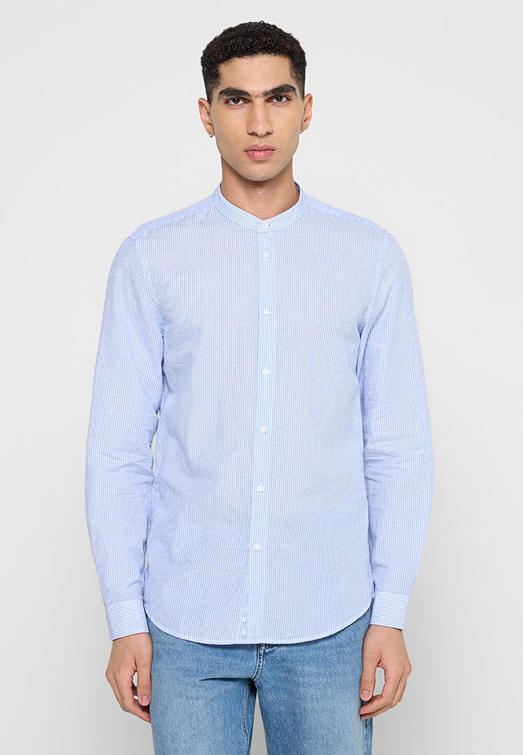 Camicetta a righe azzurro chiaro e bianco con colletto alla coreana. Maniche lunghe, vestibilità slim e una texture di tessuto di cotone morbido.