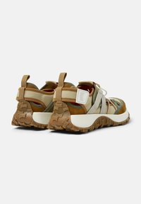 Scarpe sportive marroni e verdi con tomaia in tessuto, multiple cinghie, linguette di prensione e suole in gomma testurizzata. La intersuola bianca offre un contrasto.