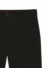 Pantaloni neri con un design a fronte piatto, chiusura con bottone e tasche frontali. Tessuto testurizzato con un logo discreto sulla cintura.