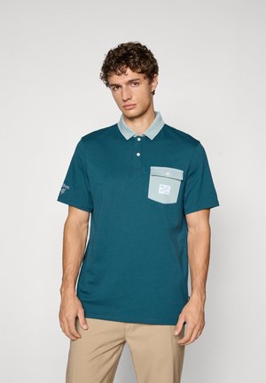 Teal polo skjorte med lys blå krage, tre knapper og brystlomme. Har brodert logo på venstre erme og glatt bomullstekstur.