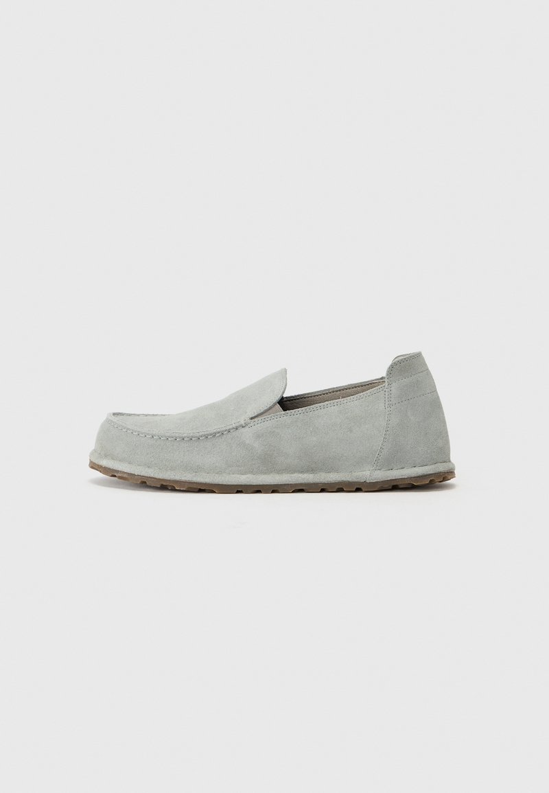Light gray suede slip-on shoe with a rounded toe, flat sole, and minimal stitching details. Smooth texture, casual design.