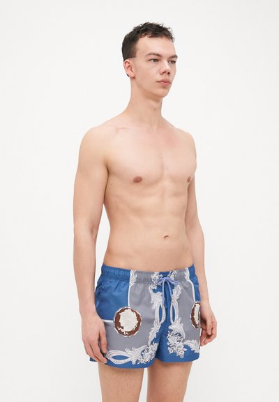 Shorts de bain pour hommes en bleu et gris, avec une finition brillante, des motifs floraux blancs ornés et des accents ronds marron. Taille élastique avec cordon de serrage.