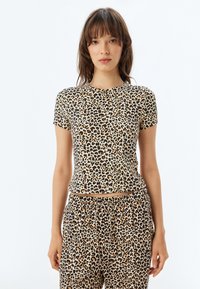 Kortærmet top med leopardprint lavet af blødt stof, med rund halsudskæring og tætsiddende silhuet. Samlet med matchende leopardprint nederdel.