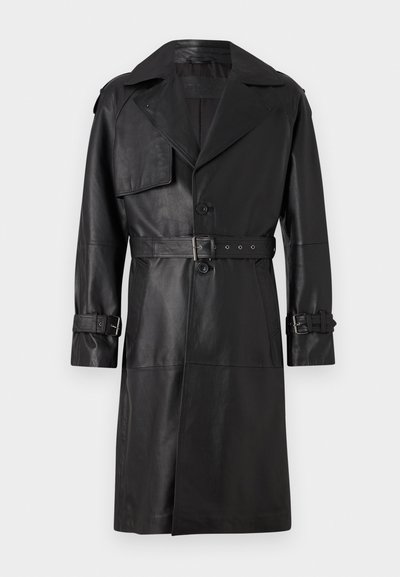 Juodas odinis tranšėjos paltas su didelėmis apykaklėmis, diržu talijoje, epauletėmis ir mygtukais ant rankovių. Lygus paviršius, iki kelių ilgio.