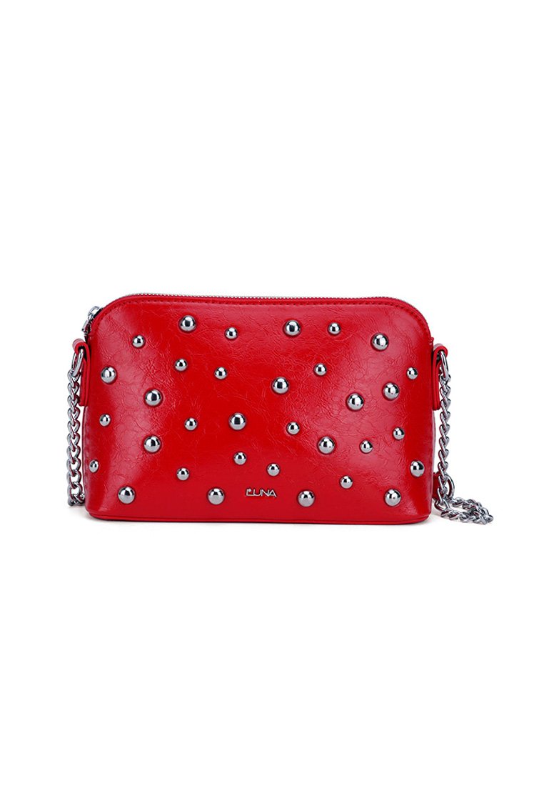 Bolso cruzado de imitación piel roja con tachuelas plateadas, cierre de cremallera y correa de cadena. Textura suave, forma rectangular, con marca notable en la parte frontal.