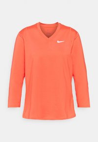 Langärmliges korallenorange Nike-Shirt mit V-Ausschnitt und weißem Nike-Swoosh-Logo auf der linken Brust, dargestellt auf weißem Hintergrund.