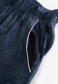 Navy blue elastic waistband pants with a subtle floral pattern and lightweight texture. Features a pink accent along the side pocket.