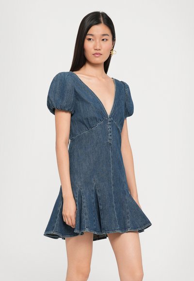 Denim kleita ar V formas izgriezumu, puff piedurknēm un platu svārku. Satur pogu detaļu pa priekšu un ir zila nokrāsa ar izbalējušu tekstūru.