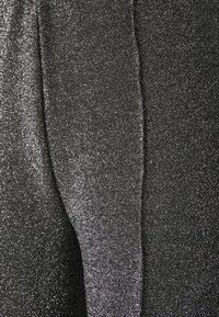 Tela negra texturizada con un brillo metálico, que presenta un detalle de costura horizontal. La superficie es brillante y suave, lo que aumenta el interés visual.