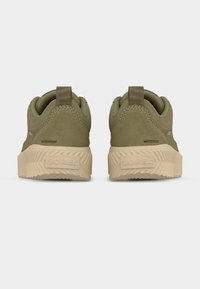 Ζευγάρι από αδιάβροχα αθλητικά παπούτσια σε ελιά πράσινο χρώμα με μπεζ υφασμένες σόλες, που φαίνονται από πίσω σε ανοιχτό γκρι φόντο.