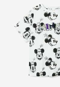 Camiseta blanca de algodón con bocetos negros de Mickey y Minnie Mouse. "MINNIE" en texto de purpurina multicolor en la parte frontal. Mangas cortas.