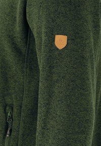 Giacca verde a maglia con tessuto testurizzato, tasca con zip e patch in pelle sul maniche sinistro.
