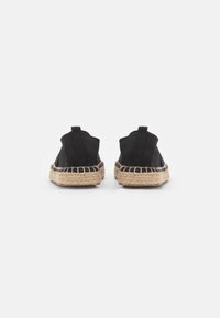 Espadrilles en toile noire avec une semelle en jute tressée. Elles présentent un bout arrondi et une languette à l'arrière pour un enfilage facile.