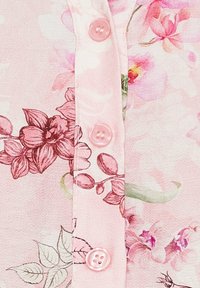 Lyserød blomster skjorte stof med lyserøde knapper. Har lette blomstermønstre i mørkere lyserød, grønne blade og en glat tekstur.