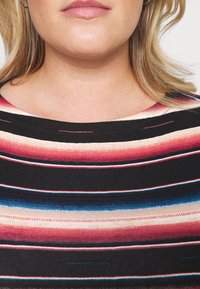 Pruhovaný top s horizontálními pruhy v červené, růžové, modré a krémové barvě na černém pozadí, s kulatým výstřihem a texturovanou tkaninou.