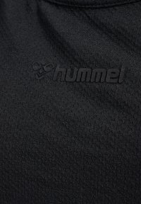 Czarna tkanina teksturowana z wypukłym czarnym logo "hummel" oraz stylizowanym symbolem trzmiela nadrukowanym na powierzchni.