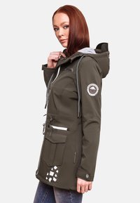 Olive green waterproof jacket with a gray hood, zippered front, side pockets, and a logo patch on the arm. Features decorative accent triangles.