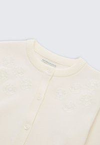 Ivory gebreide cardigan met een geribbelde kraag en gedetailleerde bloemembroideries. Voorzien van twee knopen aan de voorkant. Zachte textuur.