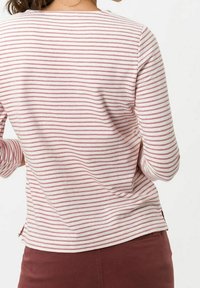 T-shirt à manches longues avec des rayures horizontales roses et blanches, fabriqué dans un tissu doux et texturé. Il présente un col rond classique et des fentes sur les côtés.