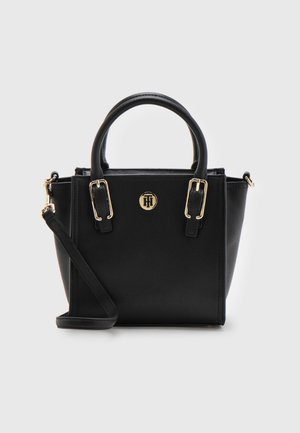 Zwarte gestructureerde handtas met dubbele handvatten, verstelbare schouderriem, hardware in goudtint en een rond logo-embleem aan de voorkant.