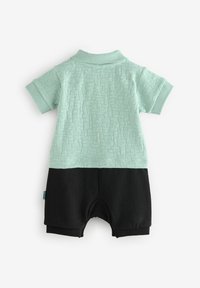 Polo-style romper i mintgrøn struktureret stof, med en ensfarvet sort nederste del. Ribbet krave og korte ærmer, materiale af bomuldsblanding.