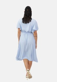 Vestido corto de color azul claro, con mangas cortas de volantes y una cinturilla elástica, que presenta una falda fluida y una textura suave.
