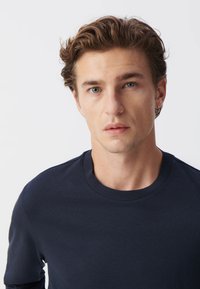Marineblaues Pullover-Sweatshirt mit Rundhalsausschnitt, aus einem glatten Stoff gefertigt. Verfügt über gerippte Bündchen und ein sauberes, minimalistisches Design.