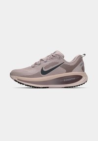 Biegowe buty Nike w jasnym mauve z ciemnozielonymi akcentami, siateczkową cholewką, teksturowaną podeszwą środkową i czarną gumową podeszwą. Zawierają znak towarowy ‘zoomx’.