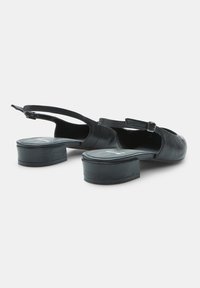 Mustad nahast slingback kingad madala plokknööpaga, avatud seljaosa ja reguleeritava rihmaga, millel on sile tekstuur ja minimalistik disain.