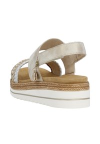 Sandale compensée avec une tige argentée métallique, des accents tressés, et une semelle intérieure beige. Elle dispose de brides ajustables et d'une semelle extérieure texturée blanche.