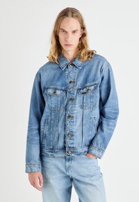 Hele sinine teksajakk nööpkinnise, kahe rinnatasku ja klassikalise kraega. Pehme tekstuur ja veidi pleekinud viimistlus.