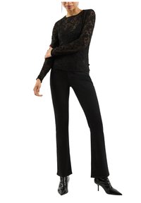 Schwarzes Spitzenoberteil mit langen Ärmeln und floralen Mustern, kombiniert mit eng anliegenden schwarzen Jeans und spitzen schwarzen Schuhen. Glatte Textur, elegantes Design.