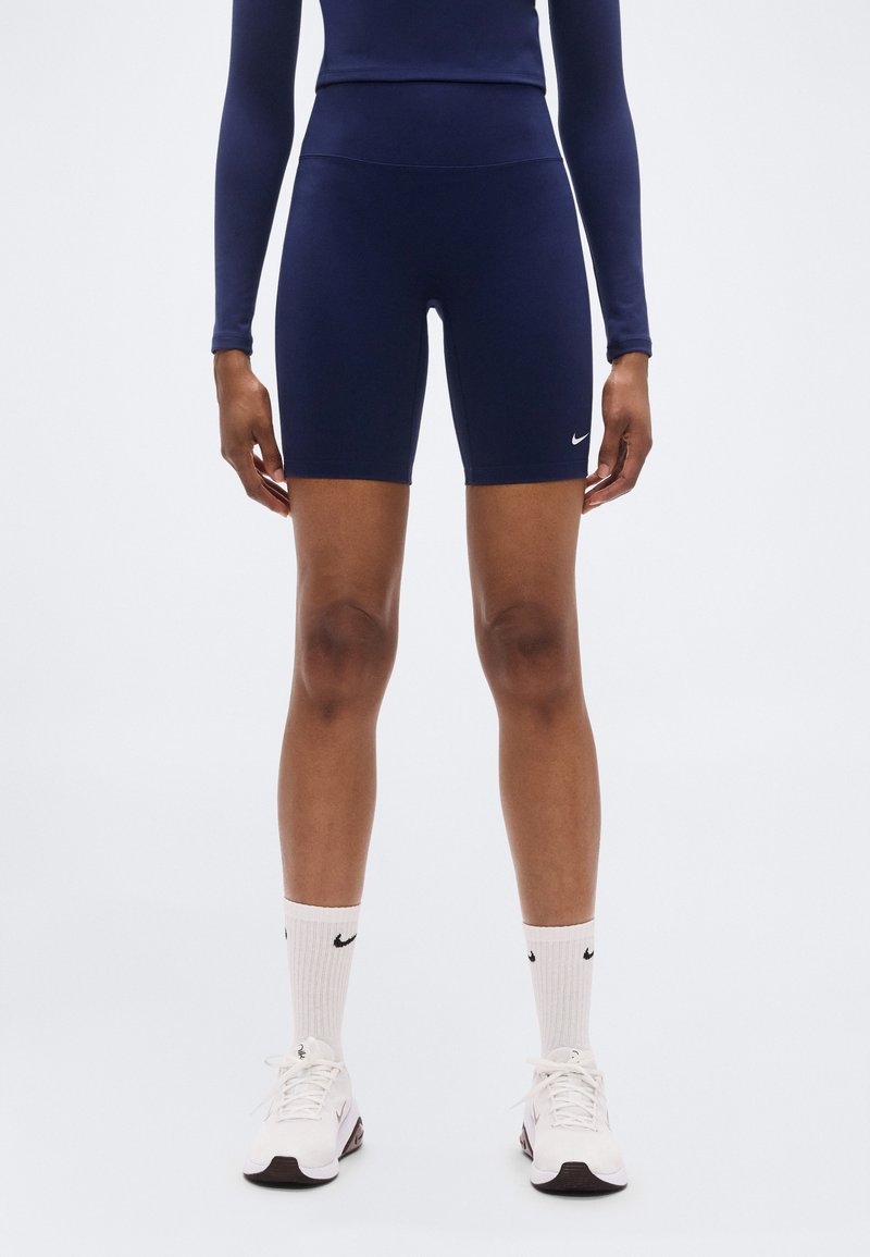 Cuissards de vélo ajustés bleu marine en matériau extensible, avec une taille haute et un petit logo Nike blanc sur la cuisse gauche.